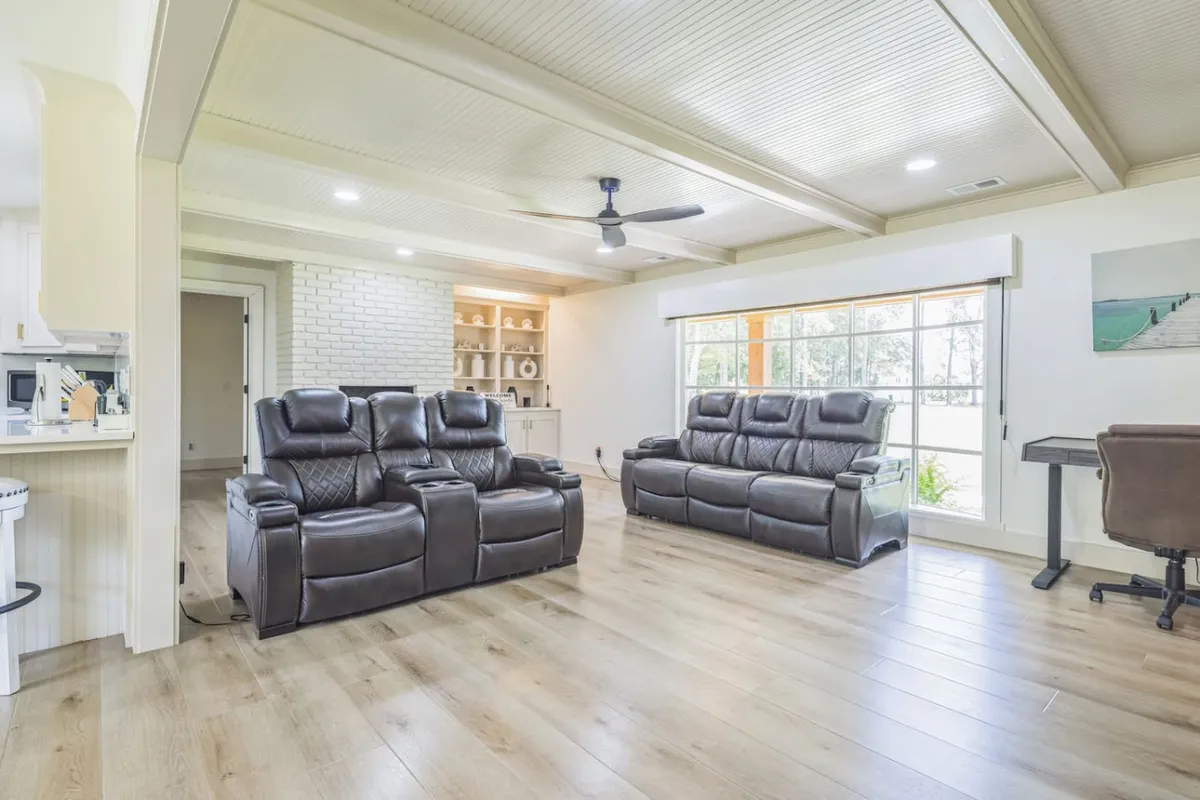A comfortable area with reclining chairs facing a large window, built-in shelving for entertainment, and a welcoming ambiance for TV viewing, socializing, or quiet relaxation. The window frames tranquil outdoor views, bringing the outside in.